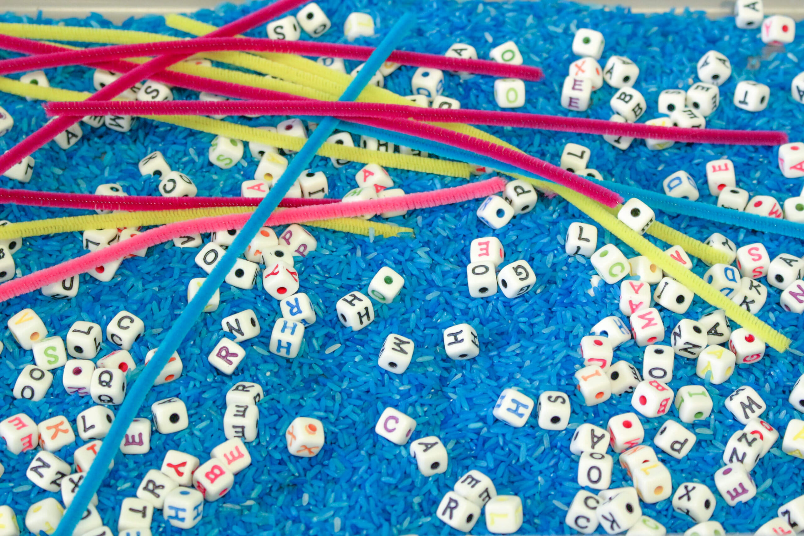 Alphabet beads and pipe cleaners sensory bin for making words
