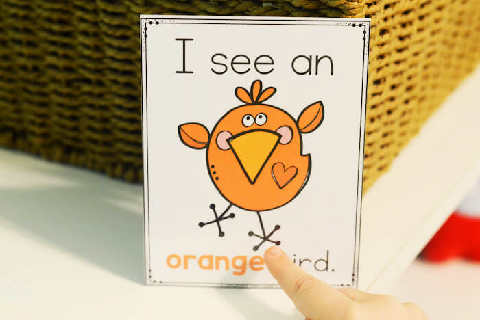 child pointing to an orange bird poster in English and Spanish colors I Spy game