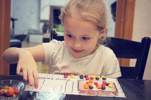 Happy child counting candies on a number mat